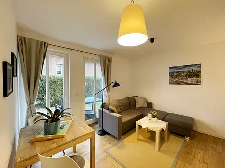 Wohnzimmer mit bequemer Eckcouch, Couchtisch, Stehlampe, 32-Zoll-Smart-TV, Bluetooth-Radio, Sideboard sowie eine Spielesammlung und kleine Auswahl an Büchern