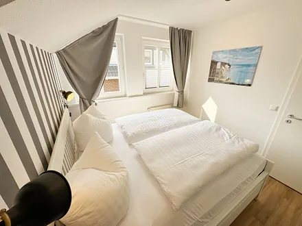 Schlafzimmer mit Doppelbett (1,60 m x 2,00 m), Wand-Nachttischlampe, verstellbare Lattenroste sowie ein geräumiger Kleiderschrank