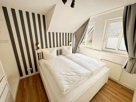 Schlafzimmer mit Doppelbett (1,60 m x 2,00 m), Wand-Nachttischlampe, verstellbare Lattenroste sowie ein geräumiger Kleiderschrank