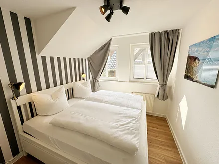 Schlafzimmer mit Doppelbett (1,60 m x 2,00 m), Wand-Nachttischlampe, verstellbare Lattenroste sowie ein geräumiger Kleiderschrank