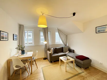 Wohnzimmer mit bequemer Eckcouch, Couchtisch, Stehlampe, 32-Zoll-Smart-TV, Bluetooth-Radio, Sideboard sowie eine Spielesammlung und kleine Auswahl an Büchern