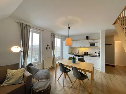 Wohnbereich mit bequemer Eckcouch, Couchtisch, Sessel, Stehlampe, 55-Zoll-Smart-TV, Bluetooth-Radio, Sideboard sowie eine Spielesammlung und kleine Auswahl an Büchern