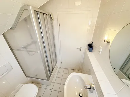 Tageslicht-Badezimmer mit Eck-Dusche, Fön, WC, Ablage, beleuchteter Spiegel, Waschplatz und ein Insektenschutzgitter