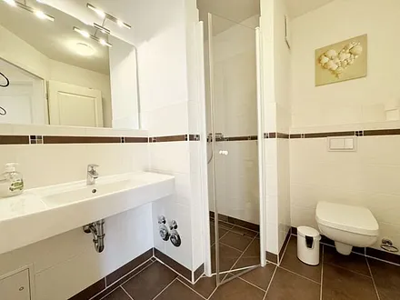 Badezimmer mit ebenerdiger Dusche, WC, Fön und Handtuchheizkörper