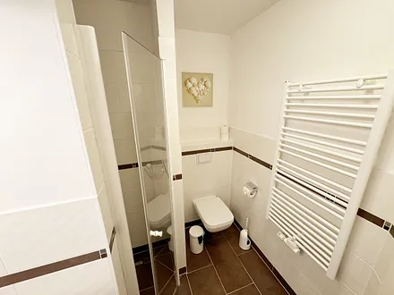 Badezimmer mit ebenerdiger Dusche, WC, Fön und Handtuchheizkörper