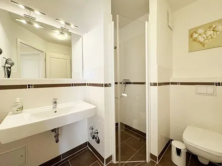 Badezimmer mit ebenerdiger Dusche, WC, Fön und Handtuchheizkörper