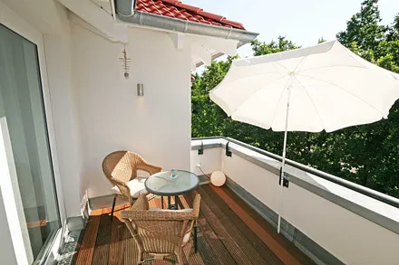 bestuhlte Dachterrasse (West) mit Bangkireiboden, Terrassenmöbel und Blick in die Baumwipfel