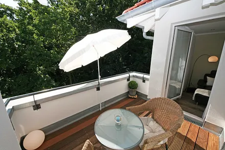 bestuhlte Dachterrasse (West) mit Bangkireiboden, Terrassenmöbel und Blick in die Baumwipfel