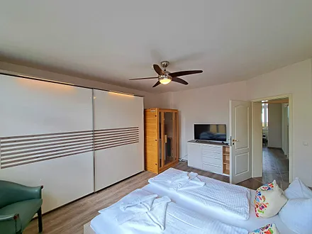 1. Schlafzimmer mit Doppelbett, TV, großem Kleiderschrank, Infrarotsaunakabine und Zugang zum Balkon