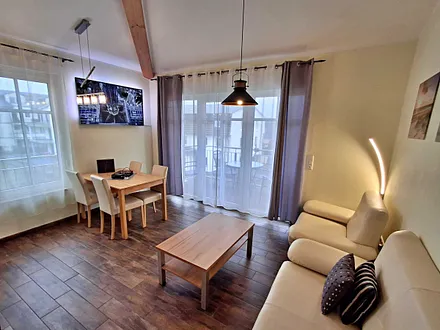 Wohn- und Essbereich mit gemütlicher Couch, Esstisch, Küchenzeile und Zugang zum Balkom