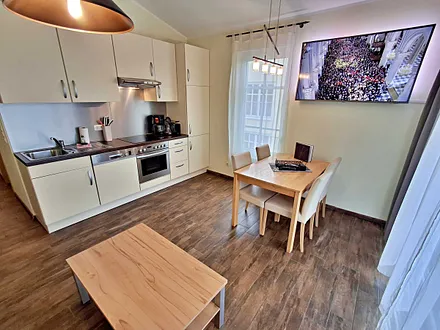 Wohn- und Essbereich mit gemütlicher Couch, Esstisch, Küchenzeile und Zugang zum Balkom