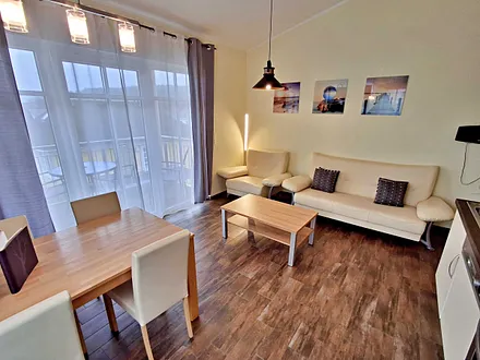 Wohn- und Essbereich mit gemütlicher Couch, Esstisch, Küchenzeile und Zugang zum Balkom