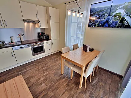 Wohn- und Essbereich mit gemütlicher Couch, Esstisch, Küchenzeile und Zugang zum Balkom