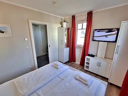 Schlafzimmer mit Doppelbett und zweitem Flachbild-TV