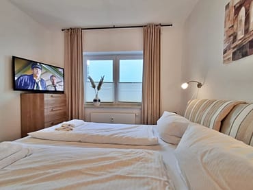 Schlafzimmer mit Doppelbett, Kleiderschrank und zusätzlichem TV