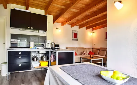 Wohnzimmer mit Schlafsofa und Küche mit Essecke