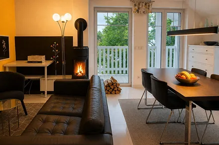 Wohnzimmer mit Kamin und Essbereich und Zugang zu zwei Balkonen.