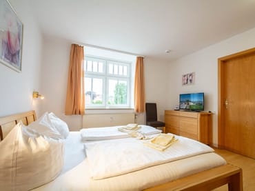 Das Schlafzimmer mit Doppelbett, Kleiderschrank und TV