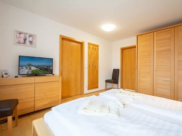 Das Schlafzimmer mit Doppelbett, Kleiderschrank und TV