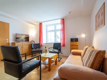 Der Wohnbereich mit gemütlicher Couch, Sesseln und TV
