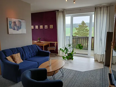 Sitzecke mit Schlafcouch in der Wohnecke, Tür zum Balkon