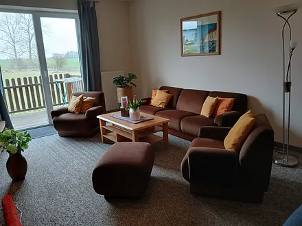 Sitzecke mit Schlafcouch und Tür zum Balkon