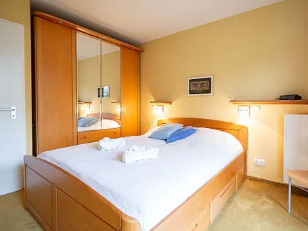 Das erste Schlafzimmer mit Doppelbett und Kleiderschrank