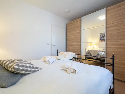 Das erste Schlafzimmer mit Doppelbett und Kleiderschrank