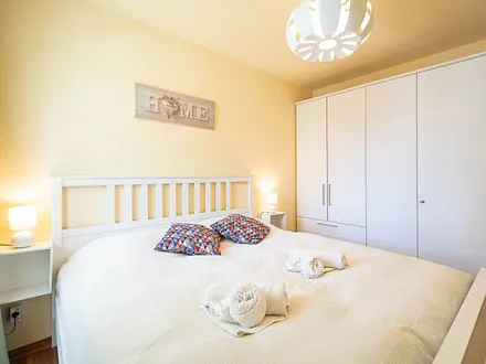 Das erste Schlafzimmer mit Doppelbett und Kleiderschrank