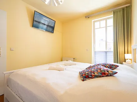 Das erste Schlafzimmer mit Doppelbett und TV