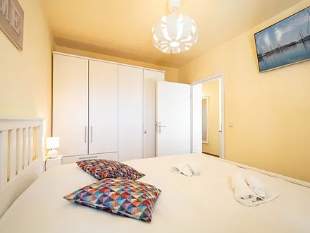 Das erste Schlafzimmer mit Doppelbett, Kleiderschrank und TV