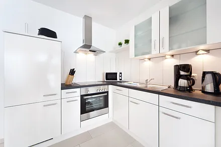 Die moderne Küchenzeile mit Geschirrspüler und Backofen im Wohnzimmer.