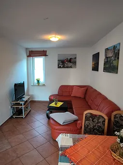 Wohnzimmer mit Schlafcouch und SAT TV 