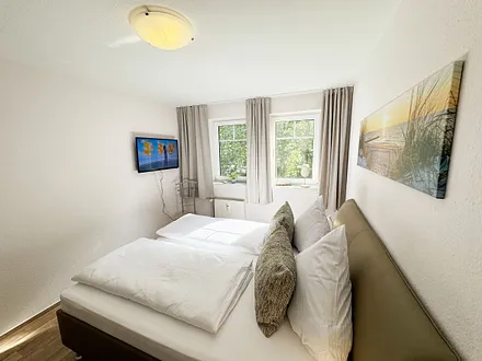 Schlafzimmer mit Doppelbett und TV