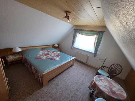 Schlafraum zur Nordseite im Obergeschoß mit Doppelbett und aufstellbarem Kinderreisebett