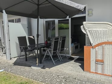 Terrasse mit Sonnenschirm und kleinem Gartenanteil