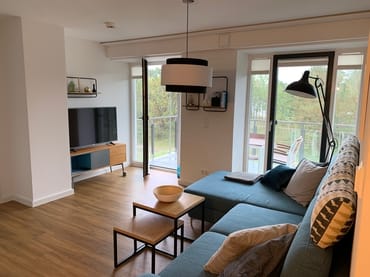 offener Wohnbereich mit Couch, Couchtisch, Stehlampe, Sideboard, Smart-TV mit Netflix Zugang, DVD-Player und Musikanlage