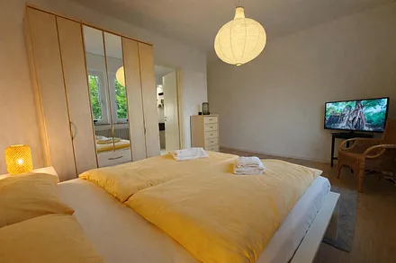 Schlafzimmer mit Doppelbett, Fernseher und eigenem Badezimmer mit Badewanne