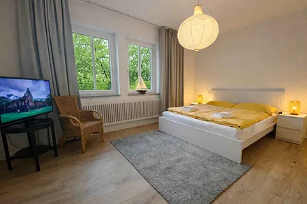 Schlafzimmer mit Doppelbett, Fernseher und eigenem Badezimmer mit Badewanne