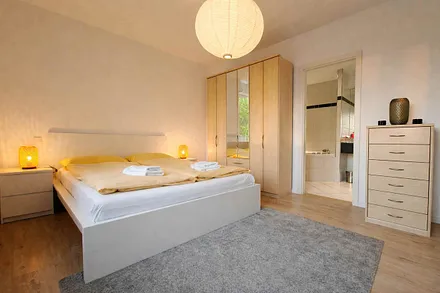 Schlafzimmer mit Doppelbett, Fernseher und eigenem Badezimmer mit Badewanne