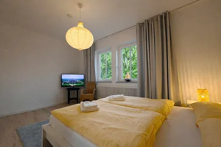 Schlafzimmer mit Doppelbett, Fernseher und eigenem Badezimmer mit Badewanne