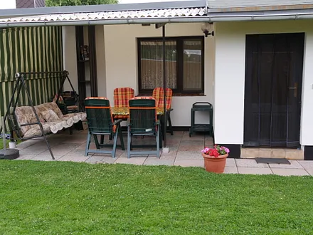 Überdachte Terrasse mit Gartenmöbel und Kohlegrill