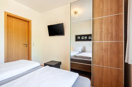 Komfortables Schlafzimmer mit Doppelbett, Fernseher und großzügigem Kleiderschrank