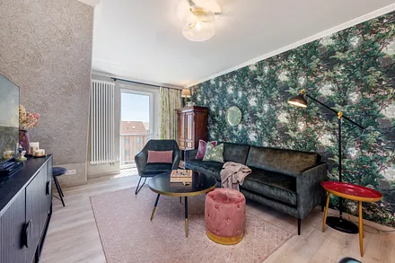 Das schöne Wohnzimmer mit samtigen Sitzmöbel, Mustertapeten und ausgewählten Antiquitäten.