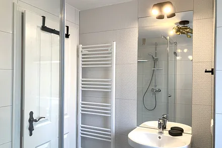 Das moderne Bad mit Echtglasdusche, WC, Fön und Fenster.