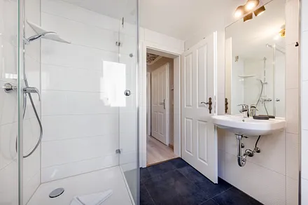 Das moderne Bad mit Echtglasdusche, WC, Fön und Fenster.