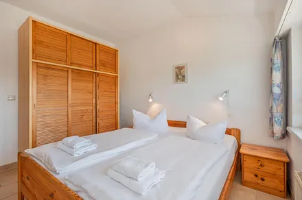 Schlafzimmer mit Doppelbett und dreitürigen Kleiderschrank