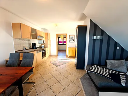 Wohnzimmer mit gemütlicher Couchgarnitur, Esstisch und Küchenzeile