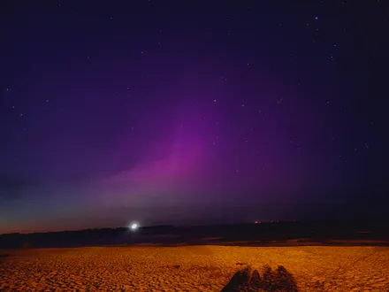 Strand bei Nacht mit Polarlichtern im Mai