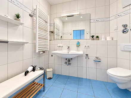 Ein maritim gestaltetes Bad mit Dusche und Fußbodenheizung gehört zum Appartment. 